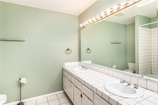 bathroom with double vanity, a sink, toilet, and tile patterned floors