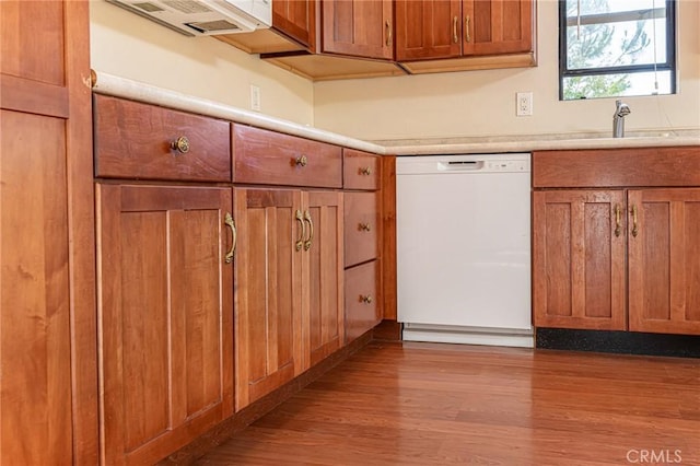 kitchen with wood finished floors, a sink, light countertops, brown cabinets, and dishwasher