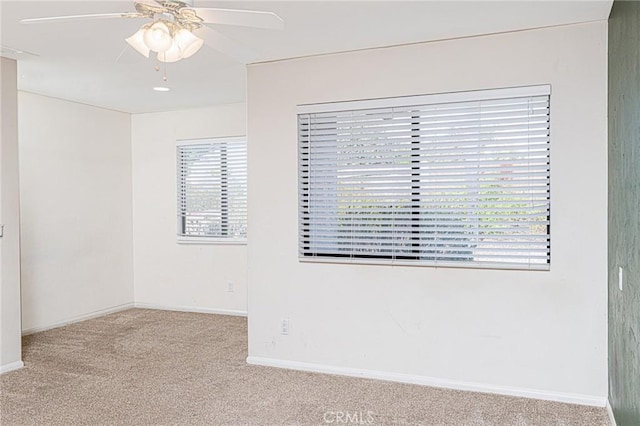 unfurnished room with carpet floors, baseboards, and a ceiling fan