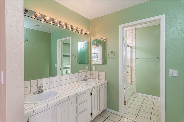 bathroom featuring tasteful backsplash, tile patterned flooring, a sink, and double vanity