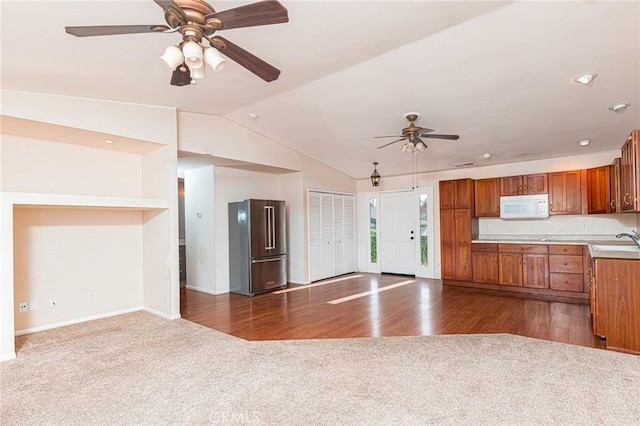 kitchen featuring open floor plan, white microwave, high end refrigerator, and a sink