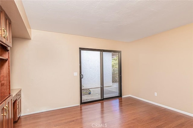 empty room featuring light wood-type flooring and baseboards