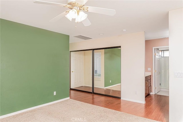 unfurnished bedroom with a closet, visible vents, baseboards, and wood finished floors