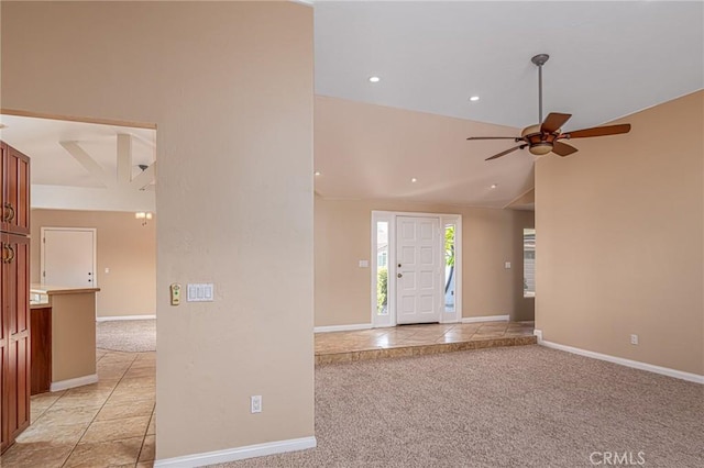 entryway with light carpet, baseboards, and vaulted ceiling