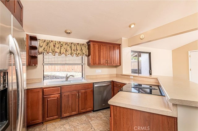 kitchen with lofted ceiling, a peninsula, a sink, light countertops, and appliances with stainless steel finishes