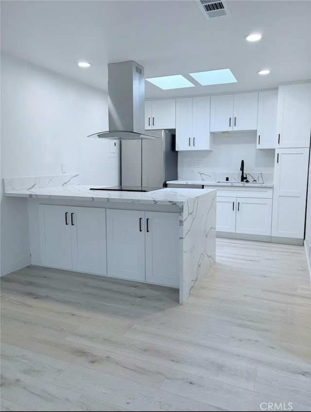 kitchen with island exhaust hood, white cabinetry, black electric cooktop, and a sink