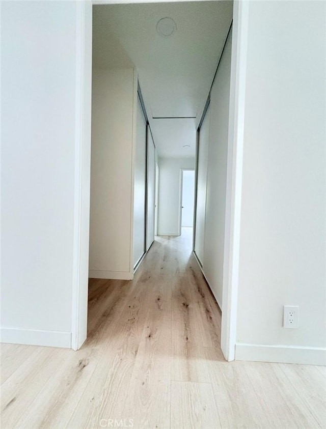 corridor with light wood-style flooring and baseboards