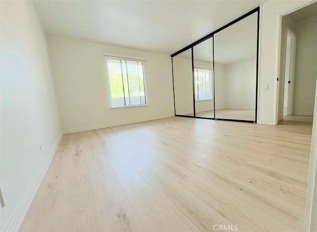 unfurnished bedroom with a closet, wood finished floors, and baseboards