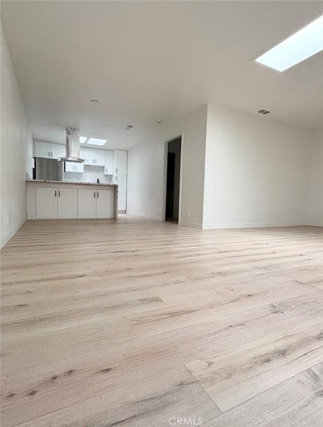 interior space featuring light wood-type flooring and a skylight