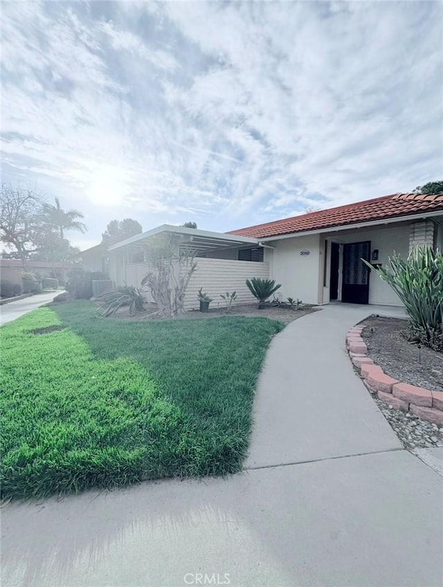 view of front of house with a front lawn, a tile roof, and stucco siding