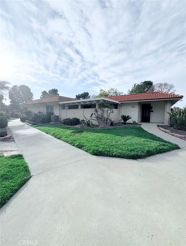 ranch-style house featuring a tile roof, a front lawn, and stucco siding