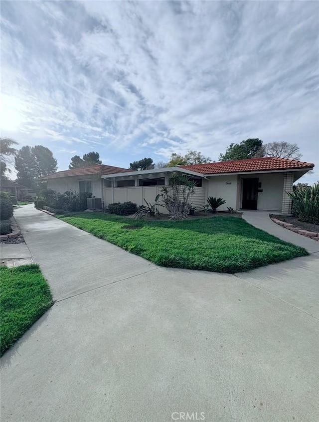 ranch-style house with stucco siding, a front yard, a tile roof, and cooling unit