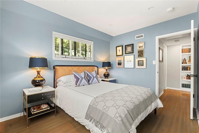 bedroom with visible vents, baseboards, and wood finished floors