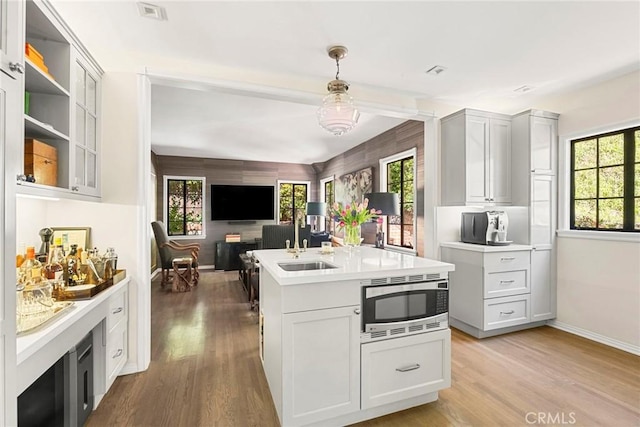 kitchen featuring open floor plan, light countertops, light wood finished floors, and stainless steel microwave