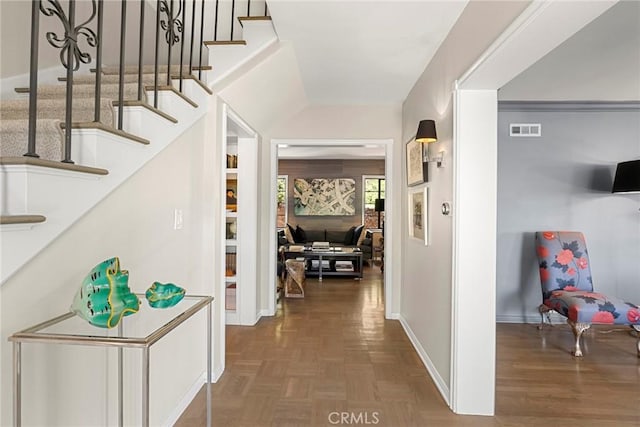 hallway featuring visible vents, stairway, baseboards, and parquet flooring