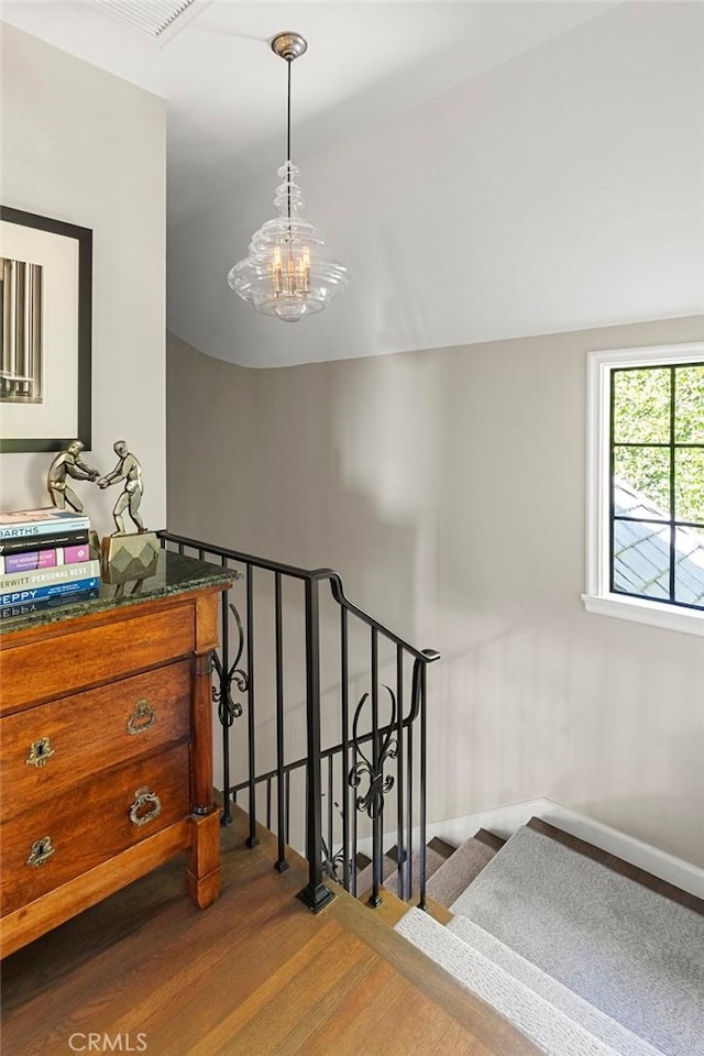 stairway featuring an inviting chandelier, baseboards, vaulted ceiling, and wood finished floors