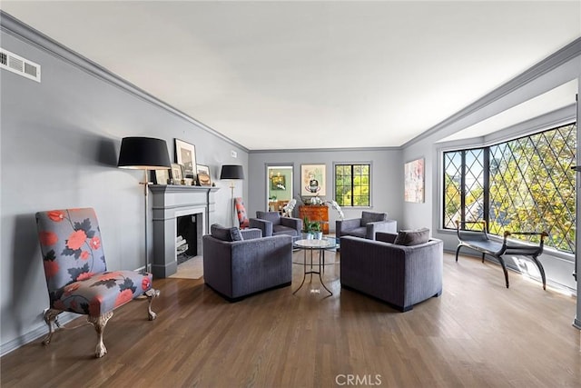 living area featuring crown molding, a fireplace, visible vents, and wood finished floors