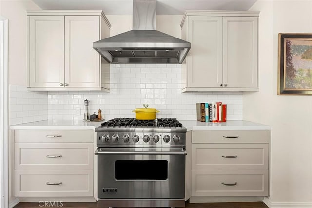 kitchen with high end stainless steel range oven, wall chimney exhaust hood, light countertops, and decorative backsplash