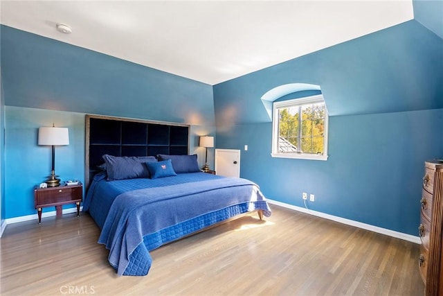 bedroom with lofted ceiling, wood finished floors, and baseboards