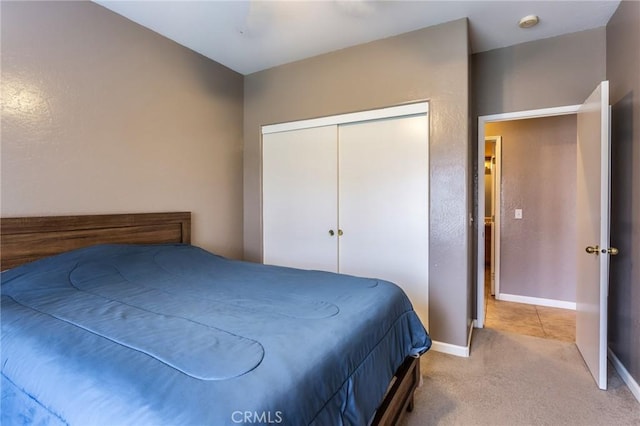 carpeted bedroom featuring a closet and baseboards