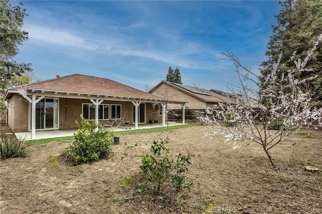 rear view of house featuring a patio area, fence, a tile roof, and stucco siding