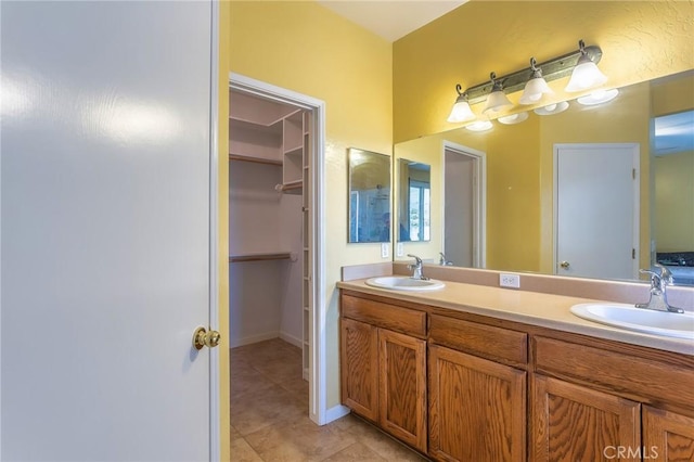 full bathroom featuring tile patterned flooring, a sink, a spacious closet, and double vanity