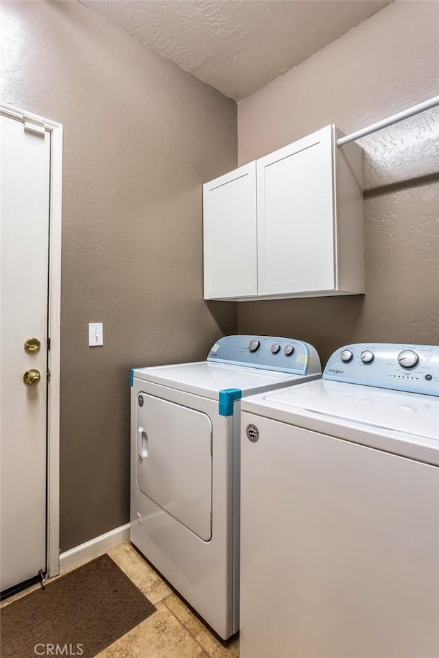 washroom with a textured ceiling, separate washer and dryer, cabinet space, and baseboards