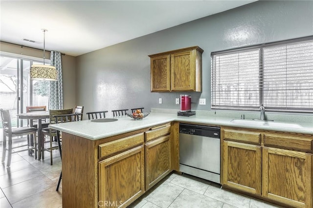 kitchen with a sink, visible vents, light countertops, stainless steel dishwasher, and brown cabinets