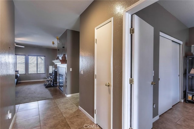 hallway featuring carpet floors, tile patterned flooring, and baseboards