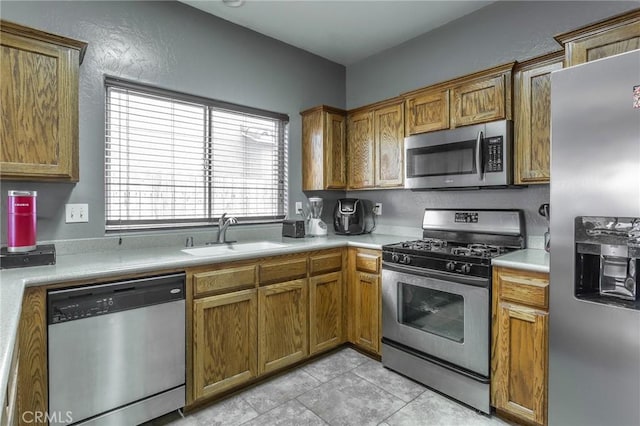 kitchen with stainless steel appliances, brown cabinetry, light countertops, and a sink