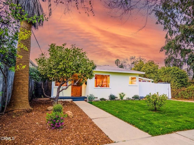 view of front facade featuring crawl space, fence, a lawn, and stucco siding