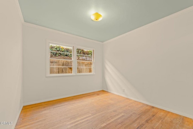 empty room featuring baseboards, wood finished floors, and crown molding