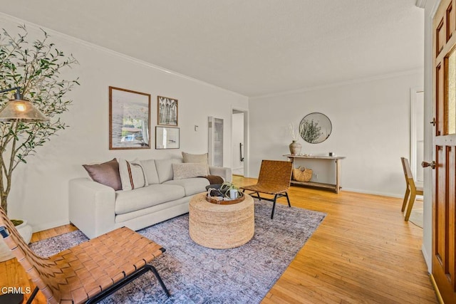 living room featuring light wood-type flooring, crown molding, and baseboards