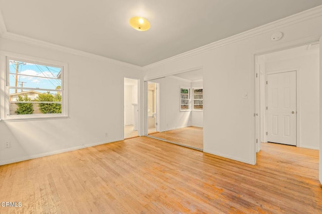 empty room featuring light wood-style floors, crown molding, and baseboards