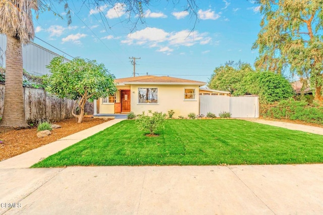 view of front of house with stucco siding, fence, and a front yard