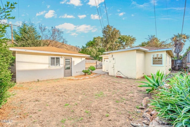 rear view of property with an outbuilding, fence, and stucco siding