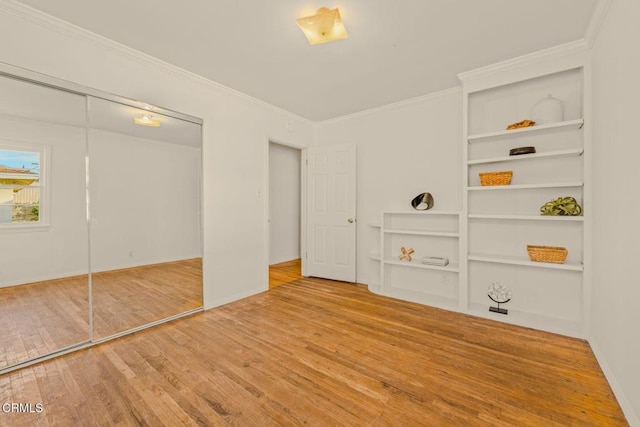 unfurnished bedroom with baseboards, a closet, wood finished floors, and crown molding