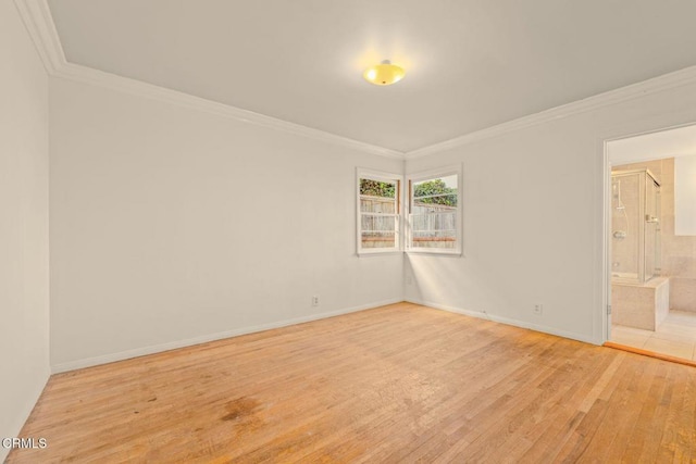 spare room featuring light wood-style flooring, baseboards, and crown molding