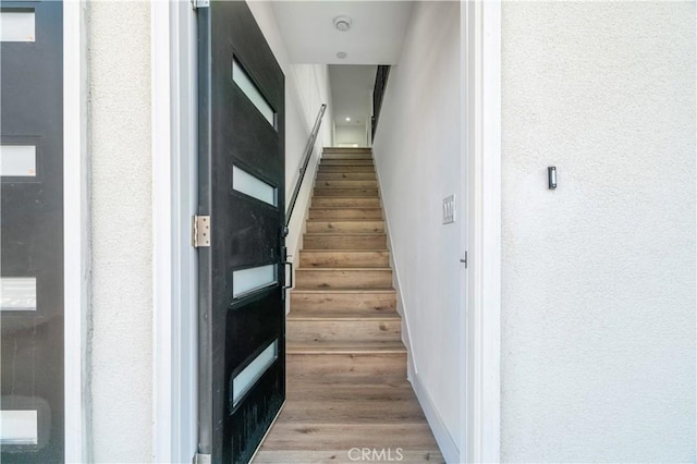 staircase featuring baseboards and wood finished floors