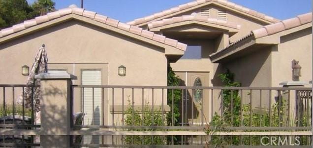 exterior space featuring a tiled roof and stucco siding