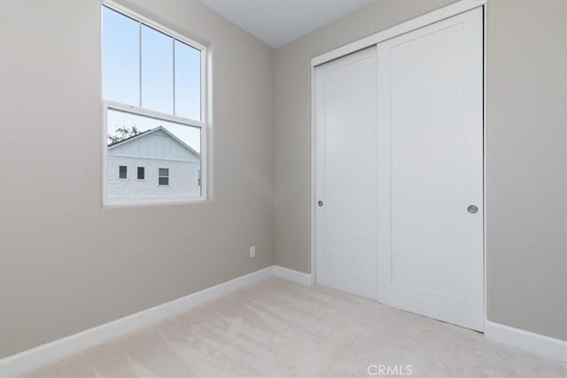 unfurnished bedroom with carpet, baseboards, and a closet