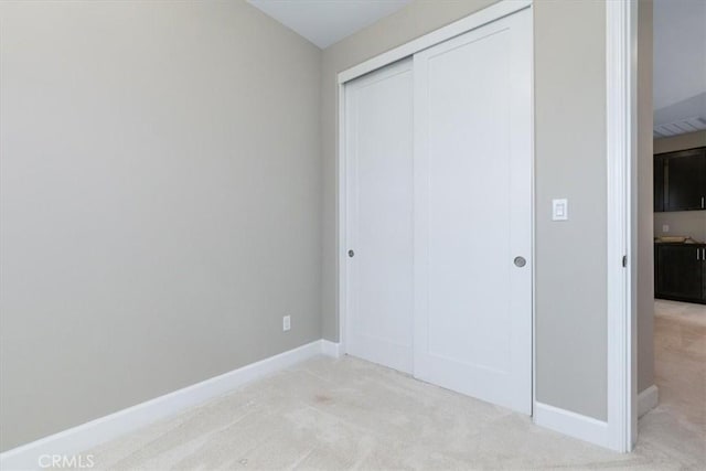 unfurnished bedroom featuring a closet, light carpet, visible vents, and baseboards