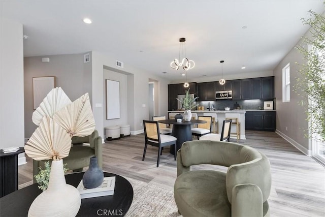 living room featuring recessed lighting, visible vents, light wood-style flooring, a chandelier, and baseboards