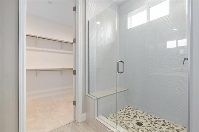 bathroom featuring a spacious closet and a stall shower