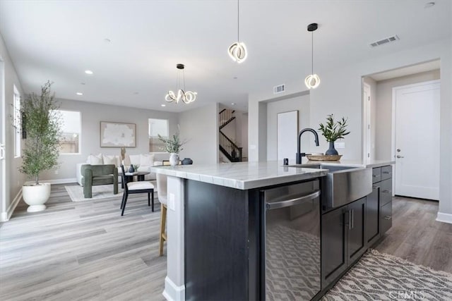 kitchen with light countertops, visible vents, hanging light fixtures, a sink, and dishwasher