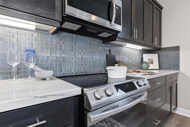 kitchen featuring baseboards, tasteful backsplash, appliances with stainless steel finishes, and wood finished floors