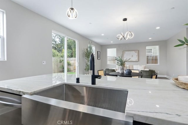 kitchen featuring recessed lighting, a sink, open floor plan, light stone countertops, and dishwasher