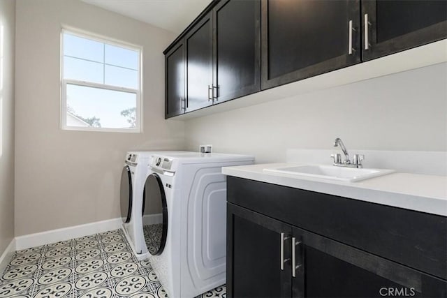 clothes washing area featuring cabinet space, light tile patterned floors, baseboards, washing machine and dryer, and a sink