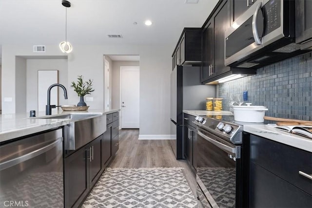 kitchen with decorative light fixtures, visible vents, backsplash, appliances with stainless steel finishes, and a sink