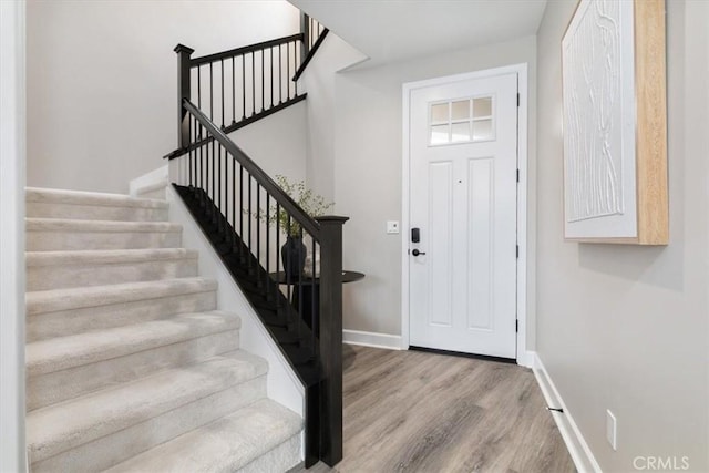 entryway featuring stairs, baseboards, and wood finished floors